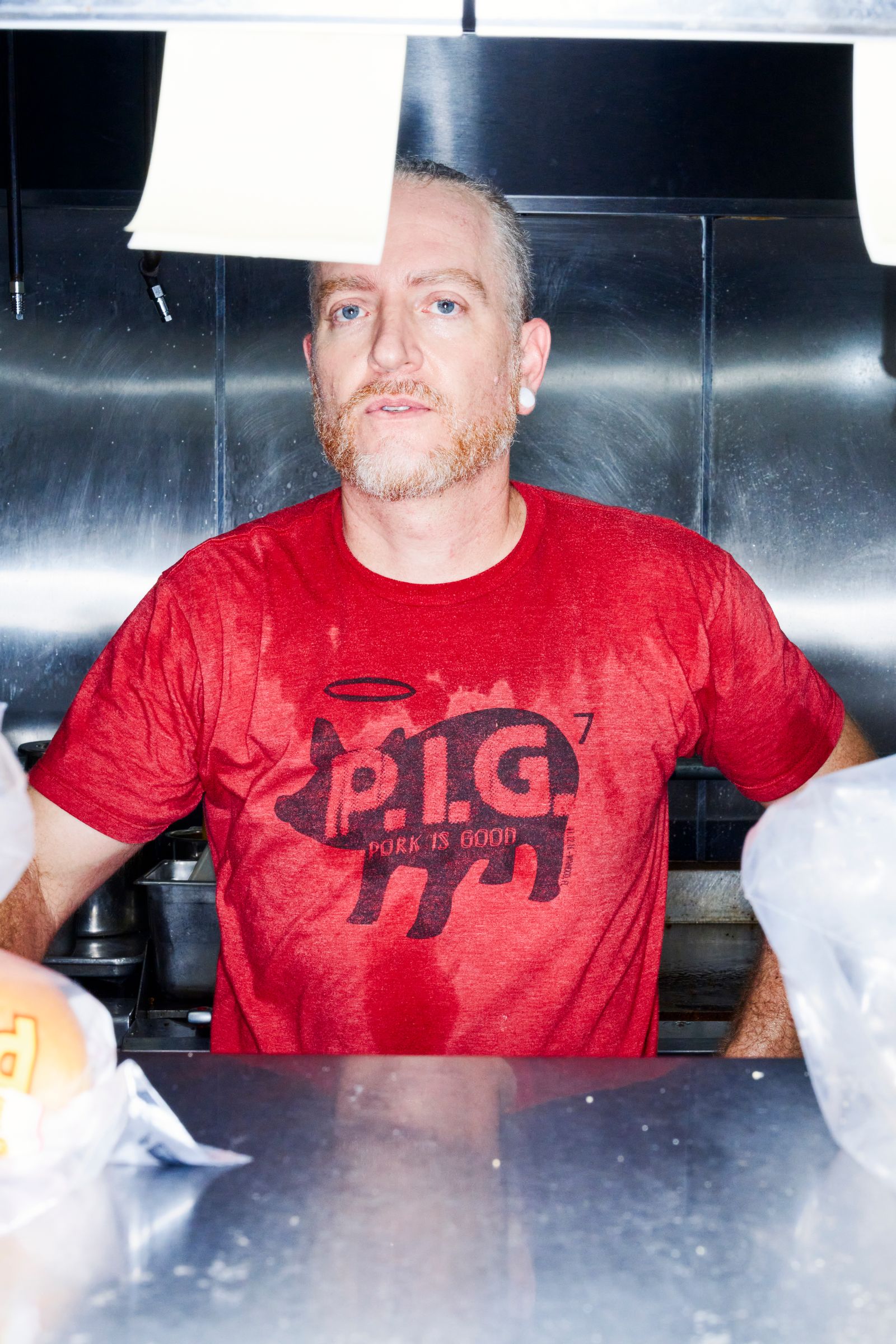 Jason Schoendorfer Coowner και σεφ στο Babes Meat and Counter σε ένα κόκκινο μπλουζάκι με ένα σιλουέτα γραφικό ενός χοίρου που ...